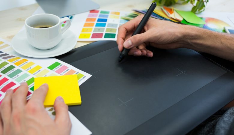 designer com paleta de cores criando identidade visual em mesa digitalizadora