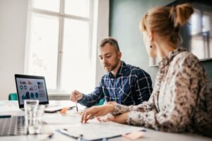 homem e mulher em uma agência analisando o retorno sobre investimento da campanha de marketing.