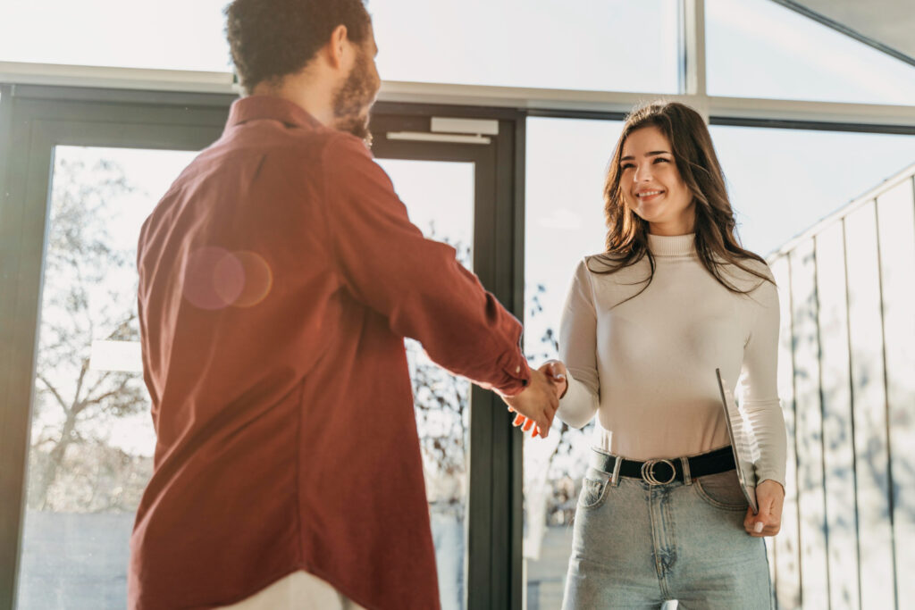 Funcionários do marketing e vendas apertando as mãos para atuar em conjunto através do SLA